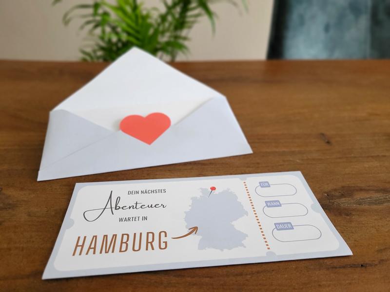 hamburg-gutschein-vorlage Hamburg Reisegutschein: Vorlage mit Briefumschlag auf Tisch